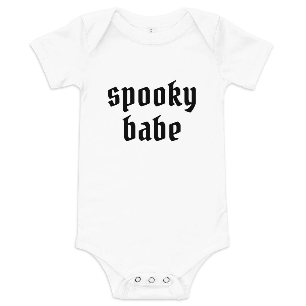 A white baby onesie that says "spooky babe" in a gothic black font