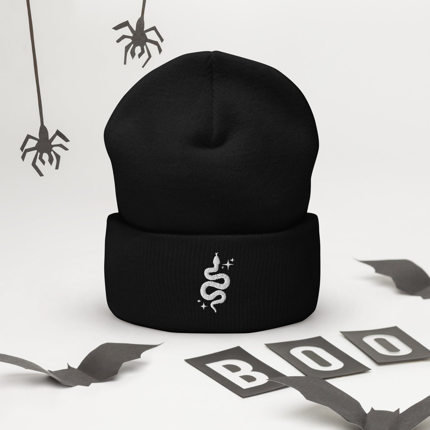 A black cuffed beanie featuring an embroidered white snake and "sparkles"