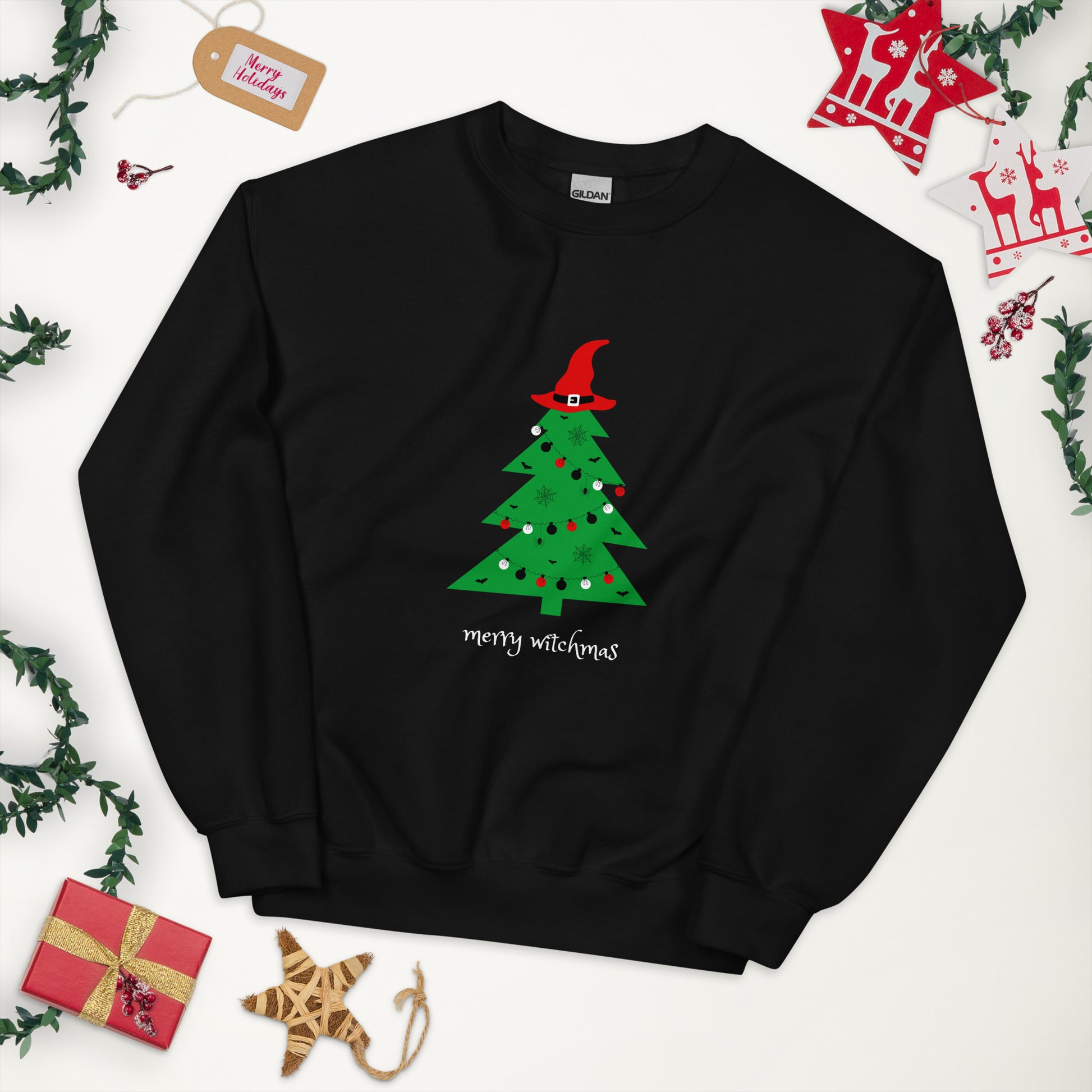 A black crewneck sweatshirt featuring a Christmas tree topped with a witch hat. The phrase "Merry Witchmas" is written underneath the tree in a whimsical white font.