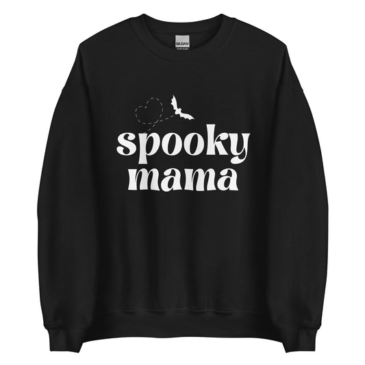 A black crewneck sweatshirt that says "spooky mama" in a white, trendy font, featuring a flying bat with a heart-shaped flight trail