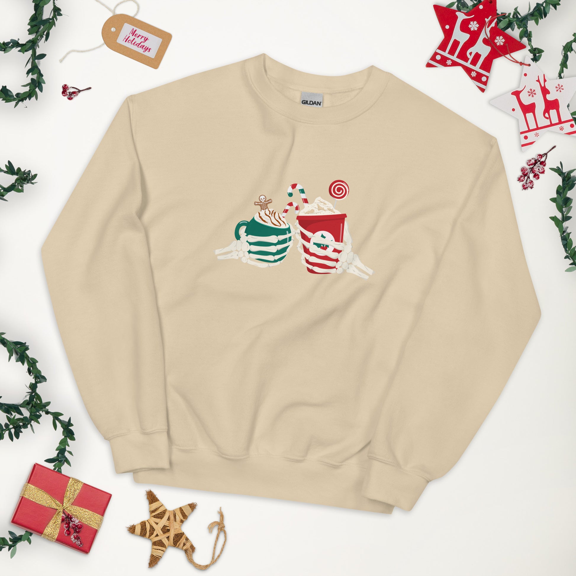 A tan crewneck sweatshirt featuring two skeleton hands holding Christmas themed coffees