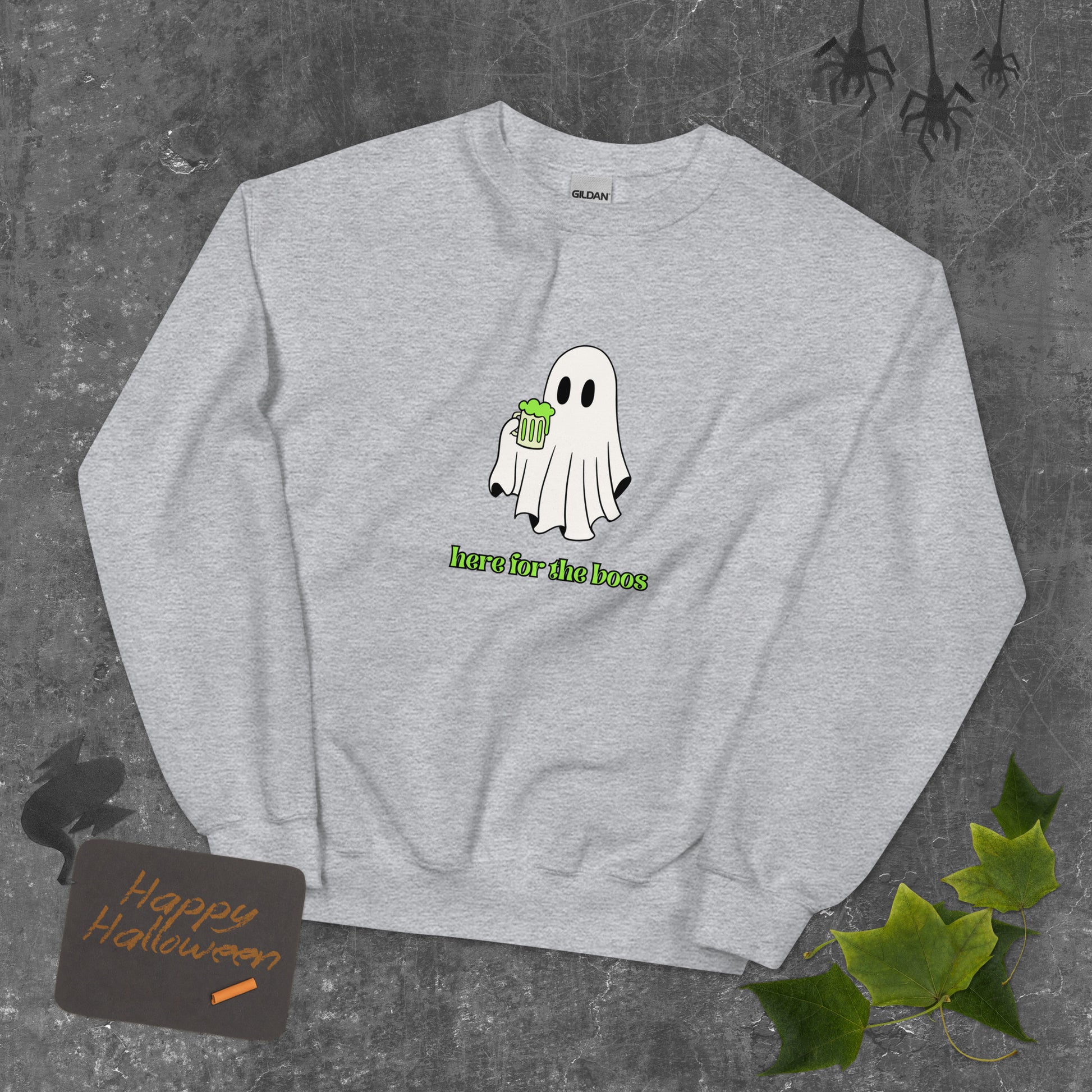 A gray Halloween crewneck sweatshirt featuring a ghost holding a mug full of something green, with the phrase "here for the boos" underneath