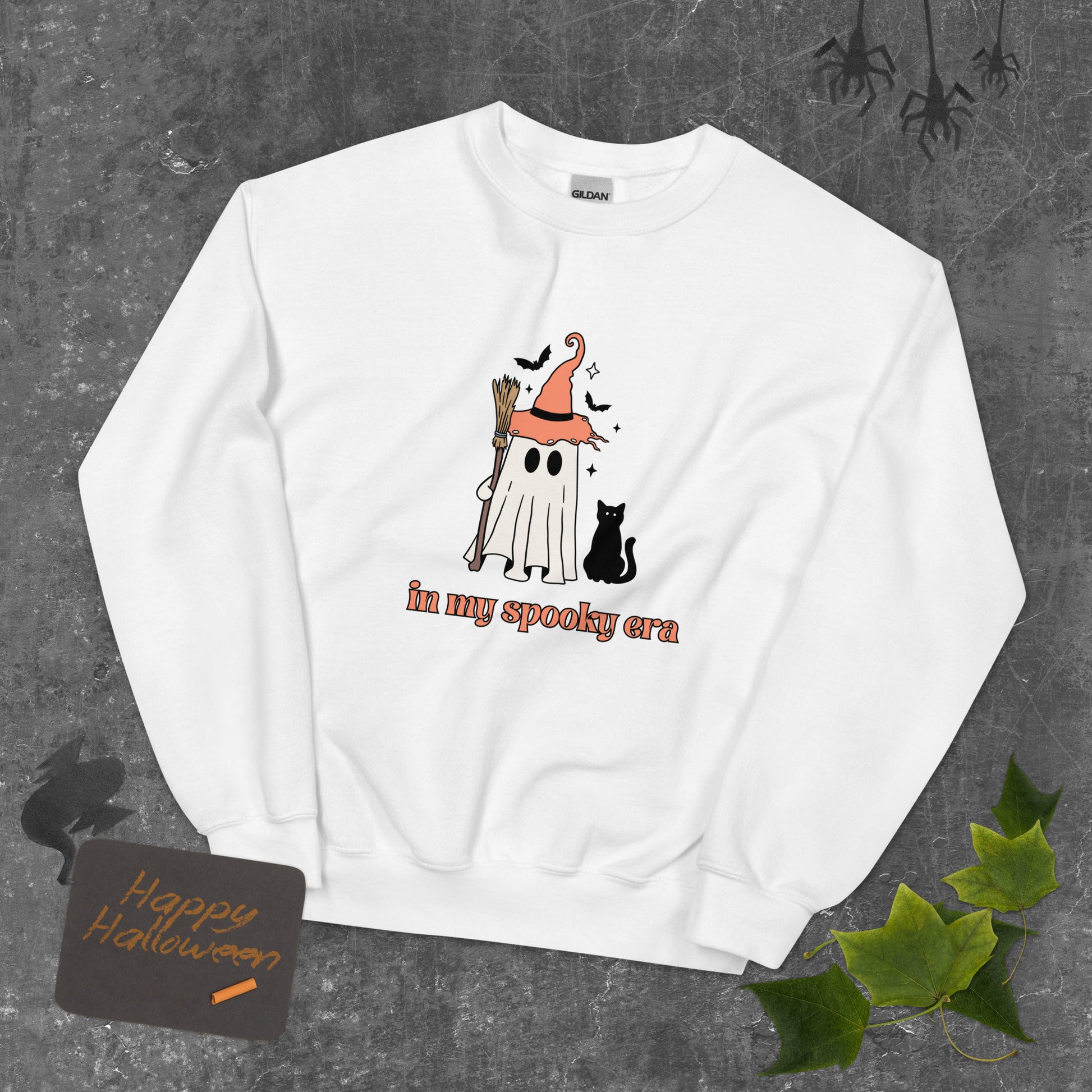 A white Halloween crewneck sweatshirt, featuring a ghost dressed up like a witch, with the phrase "in my spooky era" underneath