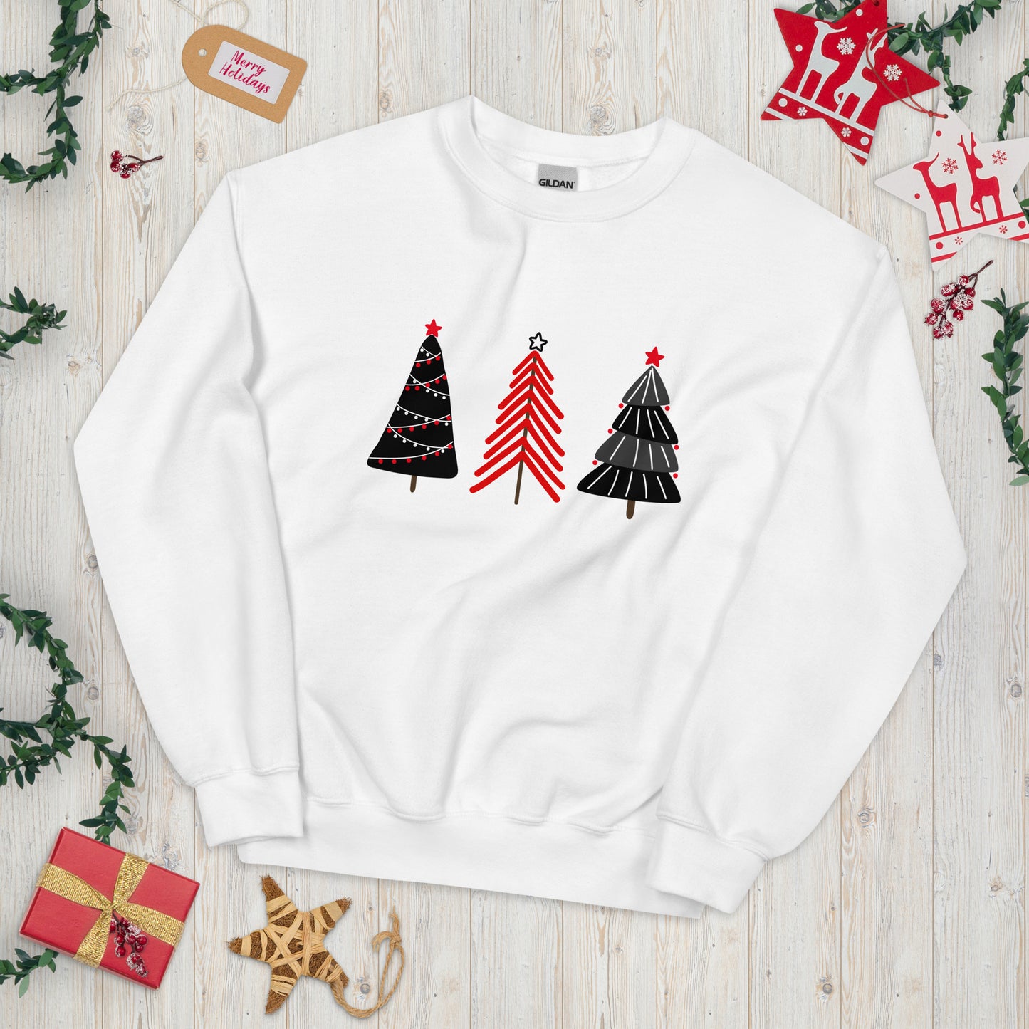 A white crewneck sweatshirt featuring three abstract Christmas trees in red and black designs