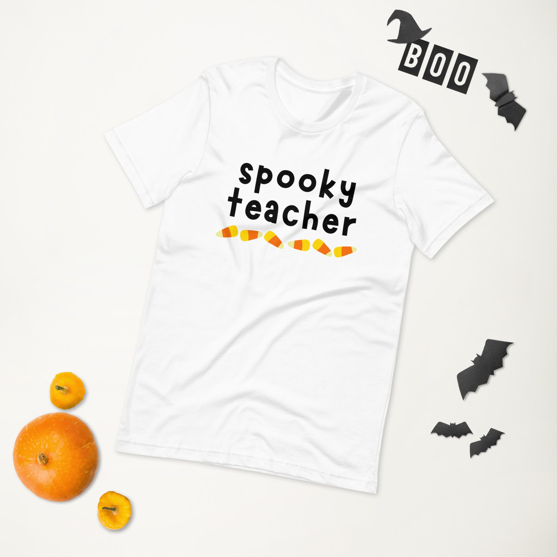 A white Halloween t-shirt that says "spooky teacher" in a cute, trendy font, above a row of candy corn