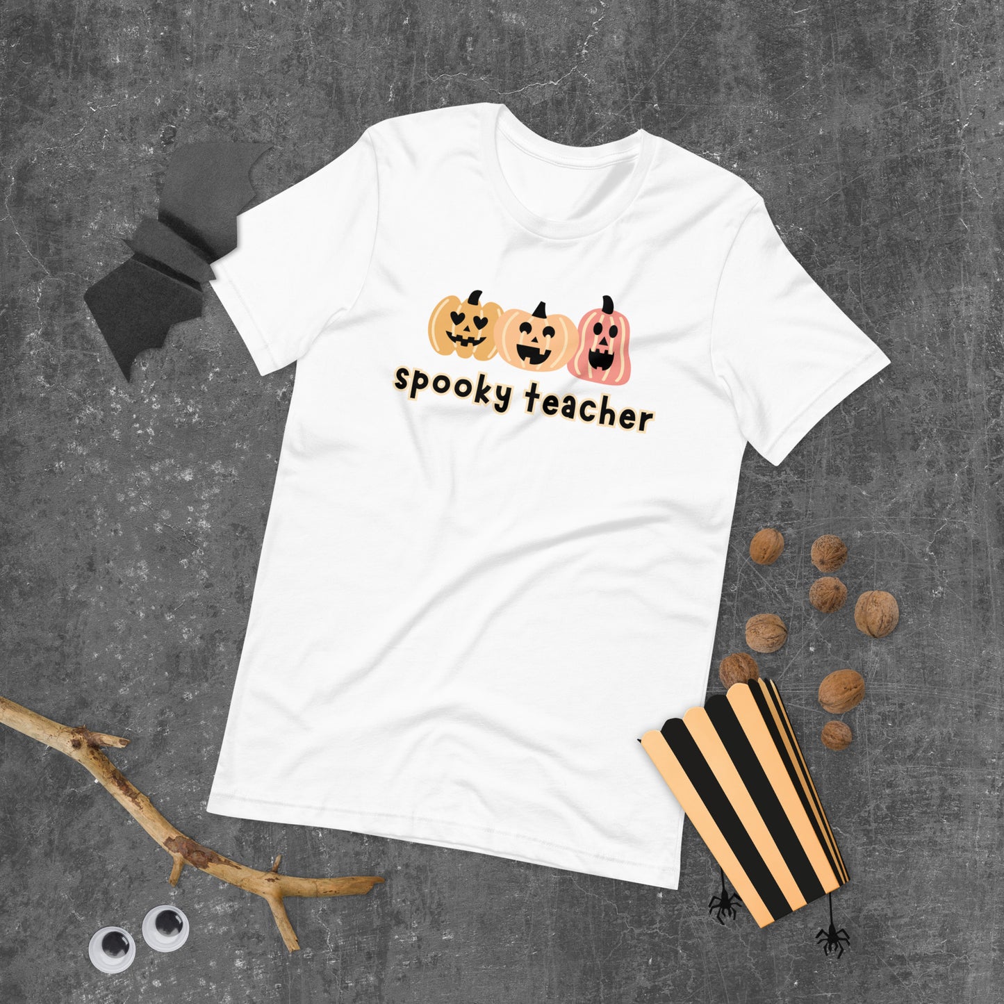 A white Halloween t-shirt featuring three cute boho-colored pumpkins with the phrase "spooky teacher" underneath