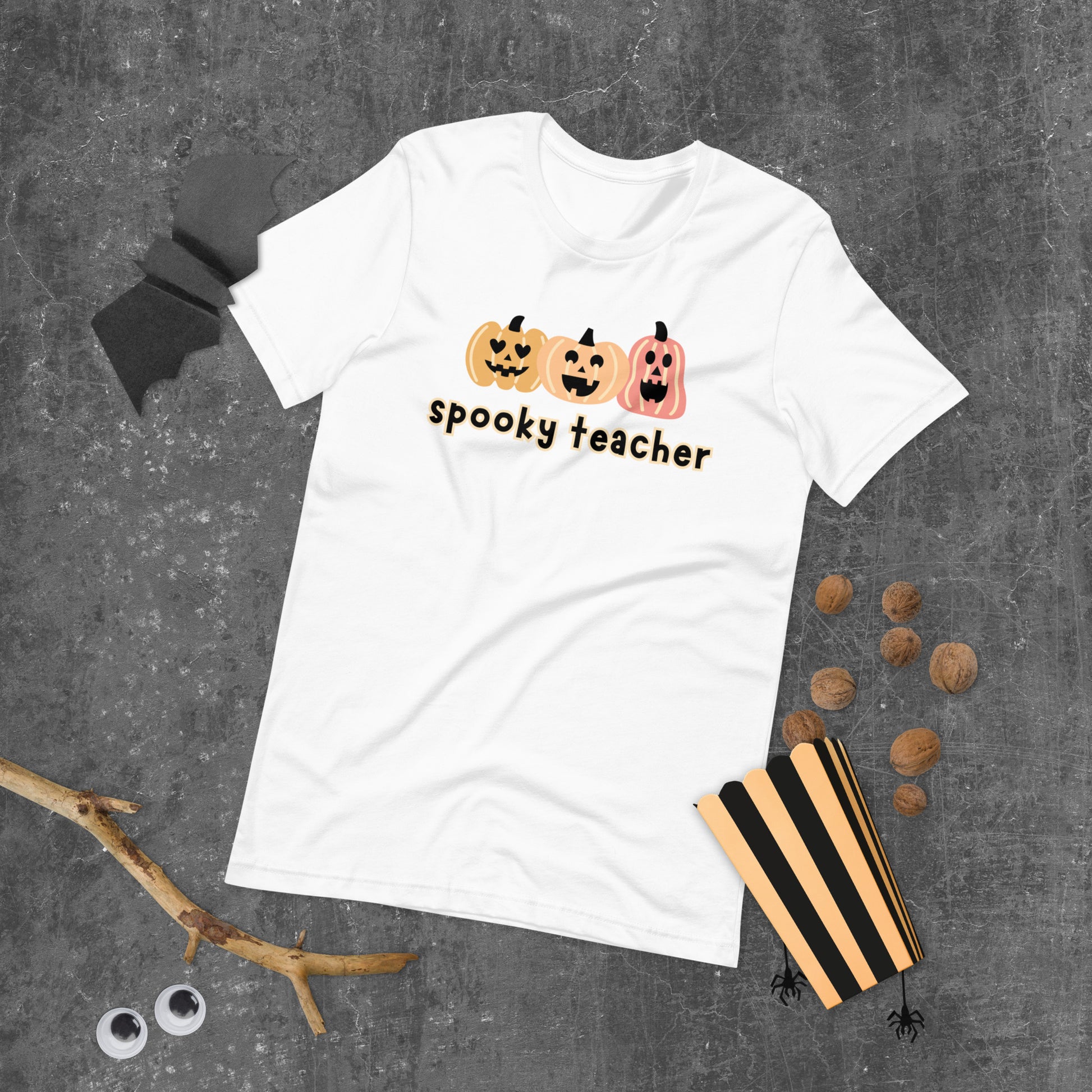 A white Halloween t-shirt featuring three cute boho-colored pumpkins with the phrase "spooky teacher" underneath