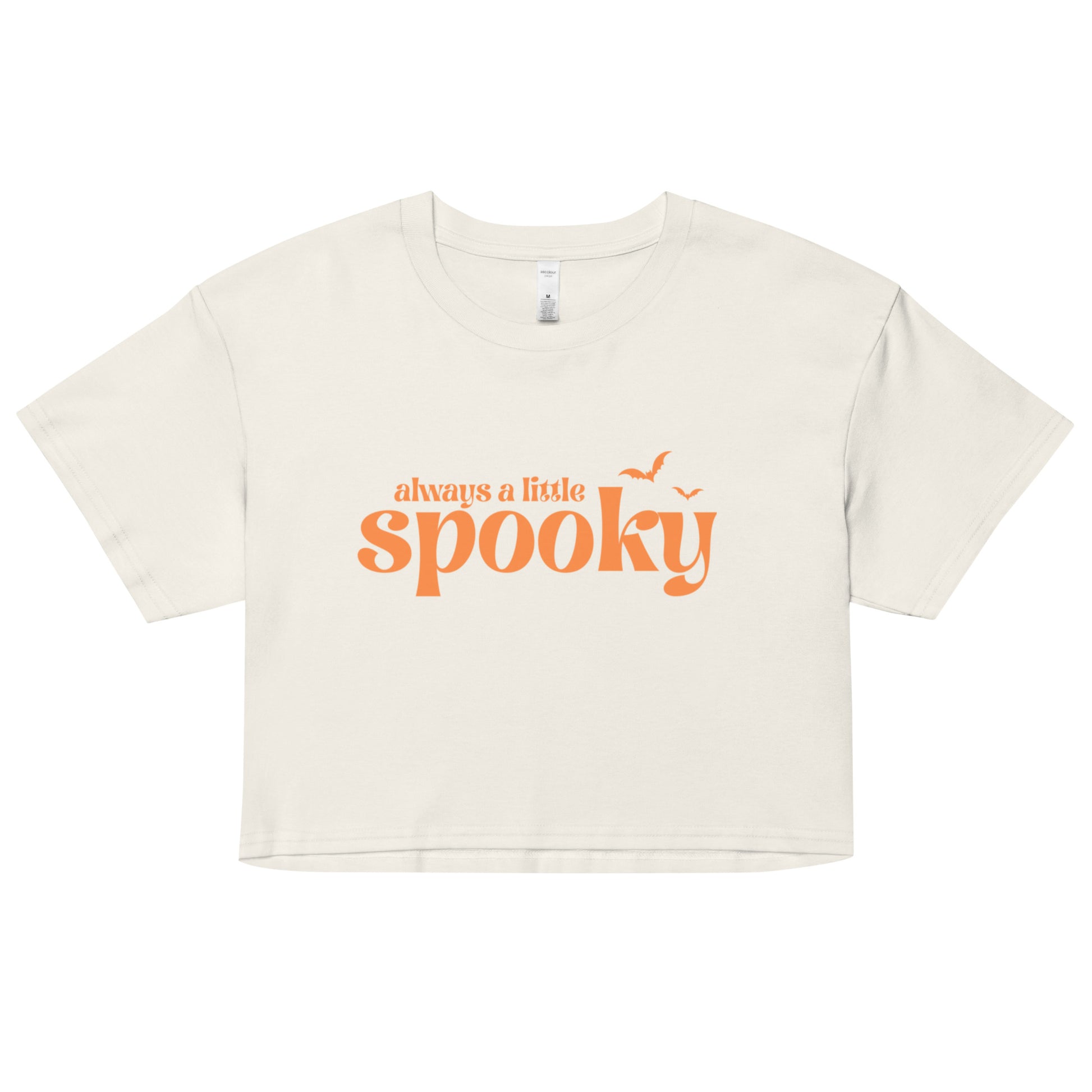 An off-white, cropped t-shirt that says "always a little spooky" in a trendy orange font