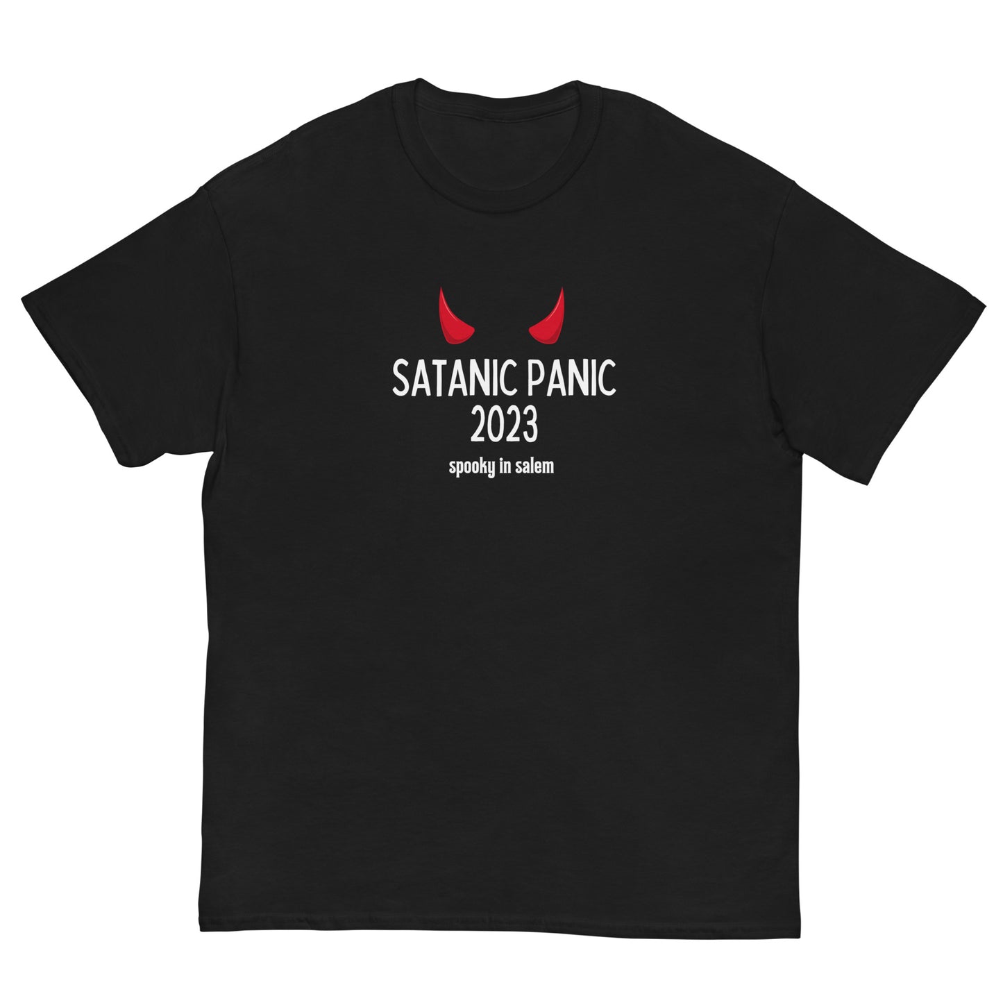 A black t-shirt featuring the phrase "Satanic Panic 2023" in white letters, with the phrase "Spooky in Salem" underneath. There is a pair of red devil horns above the main text.