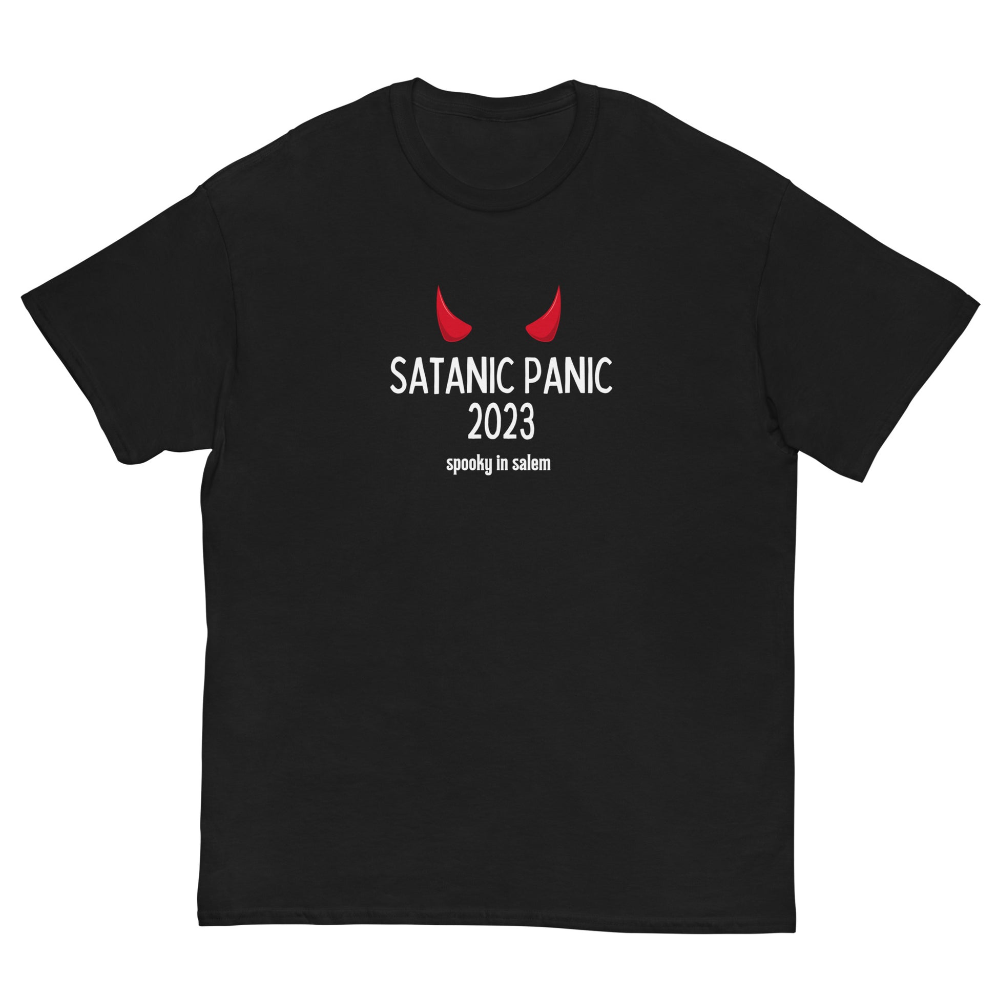 A black t-shirt featuring the phrase "Satanic Panic 2023" in white letters, with the phrase "Spooky in Salem" underneath. There is a pair of red devil horns above the main text.