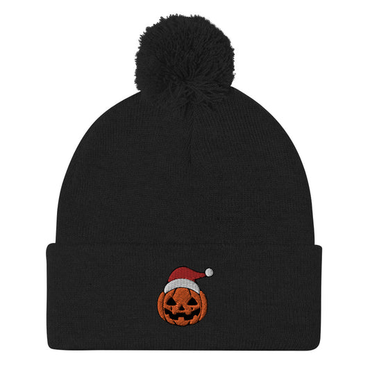 A black, cuffed, pom-pom beanie with an embroidered jack-o-lantern wearing a Santa hat