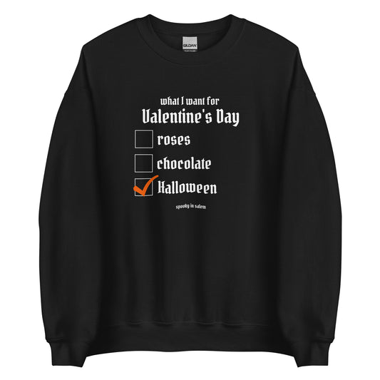 A black crewneck sweatshirt featuring a checklist titled What I Want for Valentine's Day, followed by a list of roses, chocolate, and Halloween, with Halloween checked off in orange