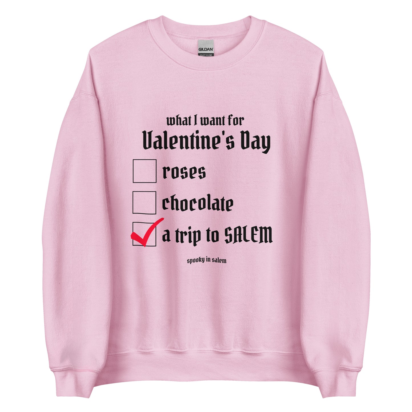 A light pink crewneck sweatshirt with a checklist in black gothic lettering. The checklist is titled What I Want for Valentine's Day, with a checklist of roses, chocolate, and a trip to Salem, which is checked off in red.