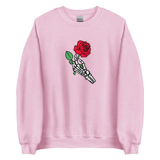 A light pink crewneck sweatshirt featuring a skeleton hand holding a red rose
