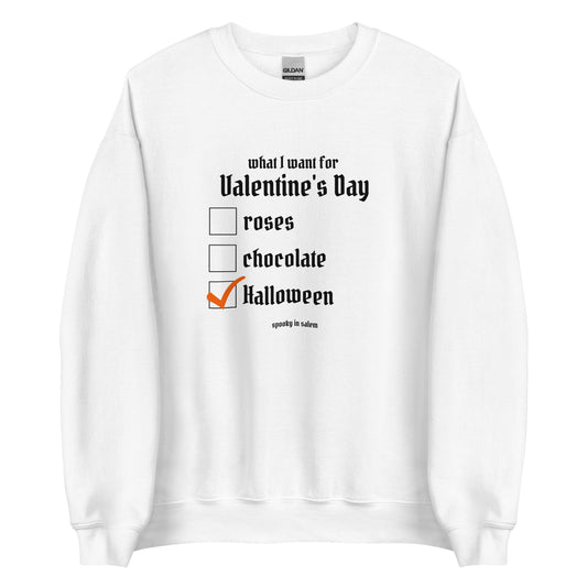 A white crewneck sweatshirt featuring a checklist titled What I Want for Valentine's Day, followed by a list of roses, chocolate, and Halloween, with Halloween checked off in orange